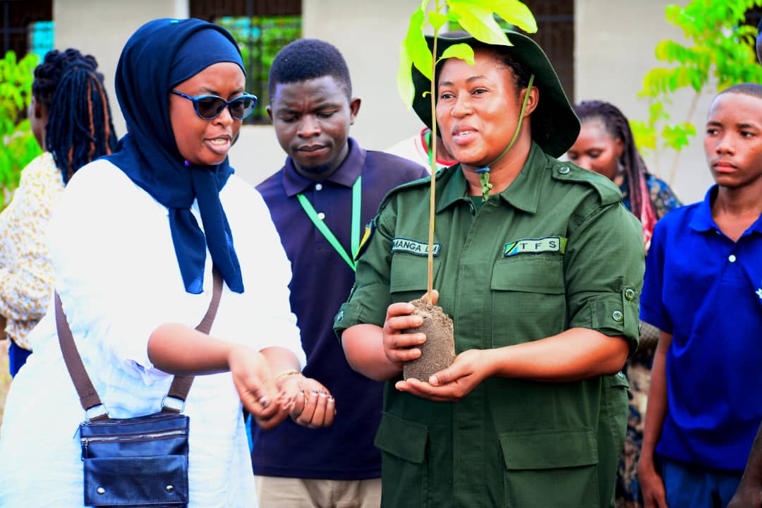 Officer handing a tree seedling to a community member